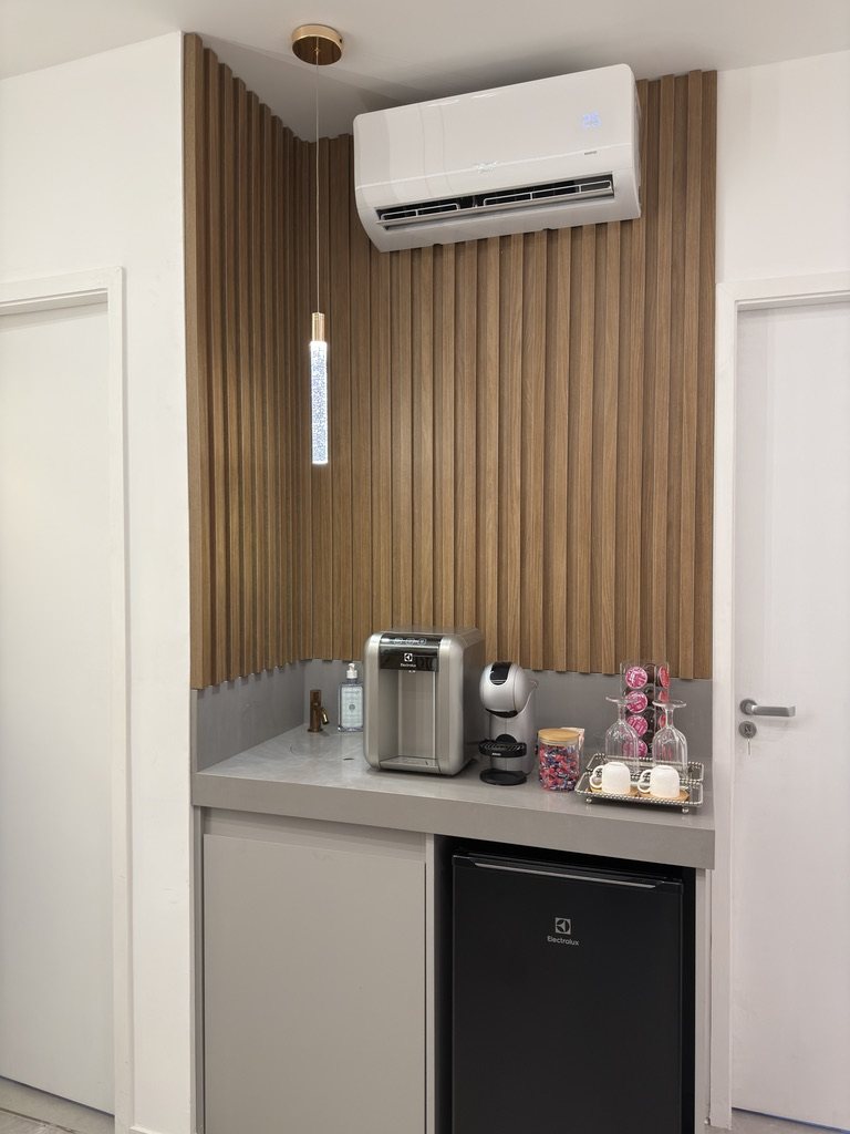 Cantinho do café com painel de madeira ripada, cafeteira e água