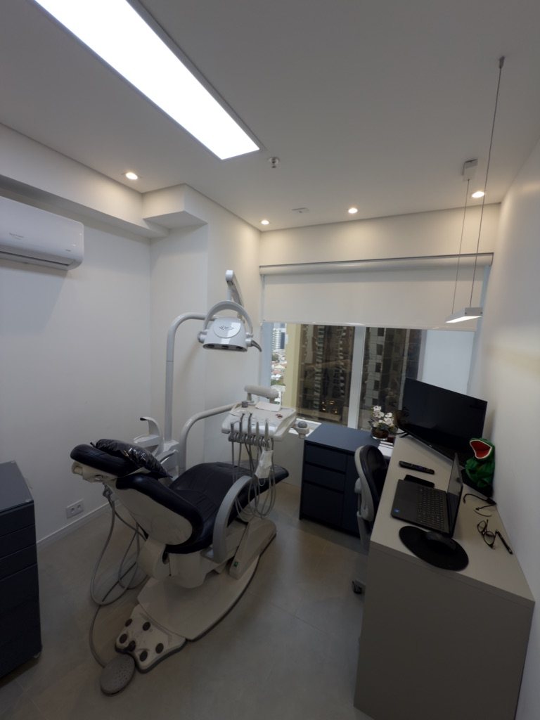 Consultório com cadeira odontológica e janela com vista para a cidade
