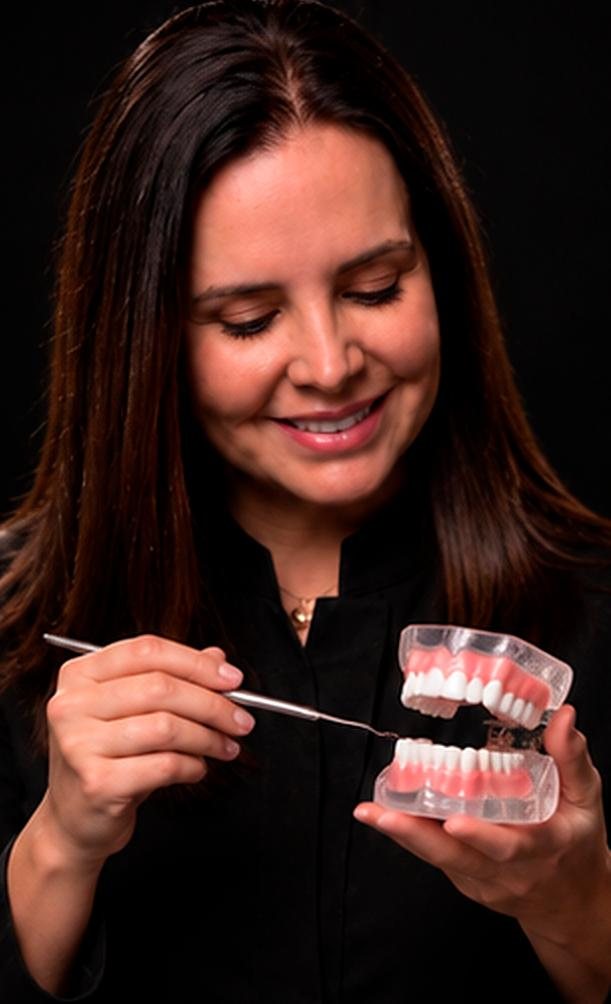 Dra. Ana Garrini explicando um tratamento com um modelo de arcada dentária